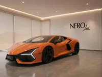 The orange 2024 Lamborghini Revuelto supercar displayed in a showroom with the NEROline logo, front three-quarter view, in Lausanne.