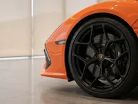 Close-up of the glossy orange front fender and black multi-spoke wheel with brake caliper of the Lamborghini Revuelto in Lausanne.