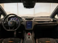 The luxurious cockpit and dashboard of the 2024 Lamborghini Revuelto in Lausanne, featuring a digital display and orange accents.