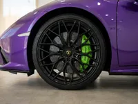 The front wheel of the Lamborghini Temerario in Gloss Metallic Purple, showcasing its black multi-spoke rim and vibrant green brake caliper in Madrid.