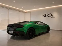 The gloss metallic green Lamborghini Temerario is showcased from a rear three-quarter angle in a modern showroom in Zurich.