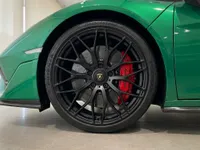 The front wheel of a gloss metallic green Lamborghini Temerario, featuring black multi-spoke rims and red brake calipers, in Zurich.