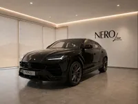 The black Lamborghini Urus is parked indoors in a modern showroom with the NEROline logo on the wall in Lausanne.