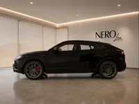 The black 2020 Lamborghini Urus, a luxury performance SUV, is showcased in a showroom with the NEROline logo in Lausanne.