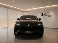 The sleek black Lamborghini Urus is showcased from the front in a modern NEROline showroom in Lausanne.