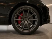 The glossy black Lamborghini Urus in Lausanne showcases its grey multi-spoke wheel with prominent red brake calipers.