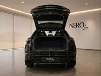 The black Lamborghini Urus is shown from the rear with its trunk open, revealing ample cargo space in Lausanne.