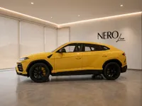 The yellow Lamborghini Urus is showcased from its side profile in a modern NEROline showroom in Lausanne.