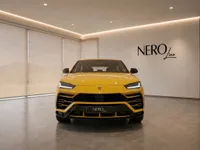 The bright yellow Lamborghini Urus is prominently displayed from the front in a sleek NEROline showroom in Lausanne.