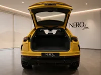 The yellow Lamborghini Urus is seen from the rear with its trunk open, revealing the spacious cargo area in Lausanne.
