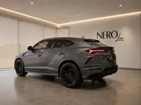 The grey Lamborghini Urus is parked in a modern showroom in Zurich, showcasing its sleek rear three-quarter profile.