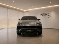 The grey Lamborghini Urus is parked head-on in a modern showroom with the NEROline logo on the wall in Zurich.