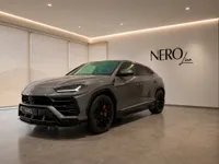 A grey 2021 Lamborghini Urus is parked at a front three-quarter angle in a modern showroom in Zurich, featuring the NEROline logo.