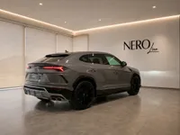 The grey Lamborghini Urus is parked indoors, showcasing its sleek rear three-quarter view in Zurich.