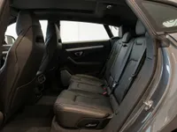 The luxurious grey Lamborghini Urus rear interior, showcasing the spacious black leather seats and door panel in Zurich.