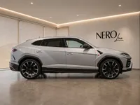The silver Lamborghini Urus is showcased in a side profile view within a modern showroom in Zurich.