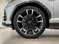 Close-up of the front wheel, tire, and lower front bumper of a silver Lamborghini Urus in Zurich, highlighting its sporty design.