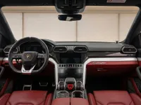 The luxurious red and black interior of the Lamborghini Urus, showcasing the steering wheel, dashboard, and central console in Zurich.