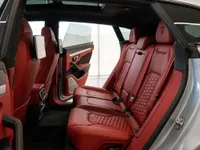 The luxurious red quilted leather rear seats and open door of the Lamborghini Urus, showcasing its spacious interior in Zurich.