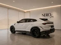 A white Lamborghini Urus Performante is showcased from a rear three-quarter view in a modern NEROline showroom in Zurich.