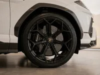 The white Lamborghini Urus Performante's front wheel, featuring black multi-spoke rims and carbon fiber accents, in Zurich.