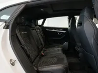 The luxurious rear interior of the white Lamborghini Urus Performante in Zurich, showcasing black Alcantara seats with hexagonal stitching.