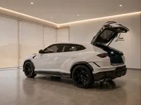 A white Lamborghini Urus Performante is shown from the rear three-quarter angle with its trunk open inside a modern showroom in Zurich.