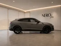 The grey Lamborghini Urus Performante, seen from the side, is parked in a modern showroom with the NERO line logo in Zurich.