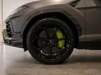 The front wheel of the Lamborghini Urus Performante in Zurich, showcasing its black multi-spoke rim and vibrant neon green brake caliper.