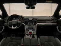 The luxurious black interior cockpit of the Lamborghini Urus Performante, featuring the steering wheel, dual infotainment screens, and front seats in Zurich.
