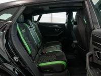 The luxurious rear interior of the black Lamborghini Urus Performante in Zurich, showcasing its sporty seats with vibrant green accents.