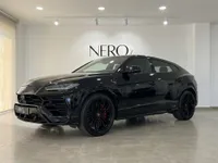 The gloss black Lamborghini Urus SE is elegantly displayed from a front three-quarter angle inside a modern showroom in Barcelona.