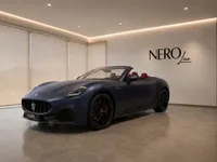The matte dark blue Maserati GranCabrio convertible is shown from a front three-quarter view in a modern showroom in Lausanne.