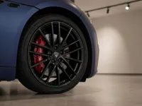 The front wheel of the Maserati GranCabrio in matte dark blue, featuring a black multi-spoke rim and red brake caliper, displayed in Lausanne.