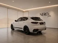 The white Maserati Levante Trofeo is showcased from a rear three-quarter angle in a modern Zurich showroom.