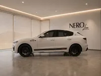 The white Maserati Levante Trofeo is presented in a modern showroom in Zurich, showcasing its sleek side profile.