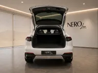 Rear view of the white Maserati Levante Trofeo with its trunk open, revealing the spacious cargo area in a Zurich showroom.