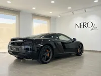 黒いマクラーレン650S MSOがマドリードのショールームに駐車されており、その洗練された後部斜めからの姿とオレンジ色のブレーキキャリパーが特徴です。