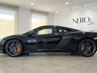 黒いマクラーレン650S MSOスーパーカーがマドリードのショールームで洗練されたサイドプロファイルで展示されており、その優雅なラインとオレンジのブレーキキャリパーが際立っています。