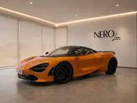 The glossy orange McLaren 750S supercar is elegantly displayed in a modern showroom in Lausanne, Switzerland.
