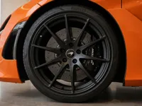 The vibrant orange front fender and black multi-spoke wheel with a McLaren brake caliper of the 2024 McLaren 750S in Lausanne.