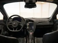 The luxurious cockpit of the 2024 McLaren 750S in Lausanne, showcasing the steering wheel, dashboard, and orange exterior accents.