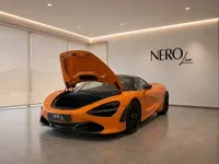 The orange McLaren 750S Spider is displayed with its front frunk open in a modern showroom in Zurich.