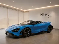 The vibrant blue McLaren 765LT supercar is showcased with its top down in a modern showroom in Lausanne.