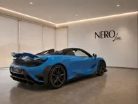 The Gloss Bright Blue McLaren 765LT Spider is shown from a rear three-quarter view in a modern showroom in Lausanne.