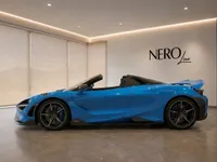 The glossy bright blue McLaren 765LT Spider is elegantly displayed from its side profile indoors in Lausanne.