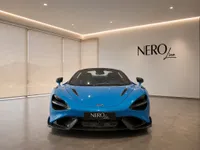 The Gloss Bright Blue McLaren 765LT Spider, a luxury supercar, is showcased from the front view in a showroom in Lausanne.