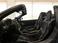 The luxurious cockpit and black Alcantara seats of the McLaren 765LT Spider in Lausanne, seen from the open door.
