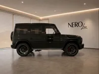 The black Mercedes-AMG G 63 is showcased in a modern Zurich showroom, displaying its powerful side profile and red brake calipers.