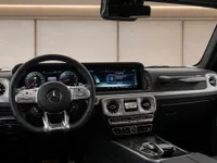 The luxurious cockpit and dashboard of the 2022 Mercedes-AMG G 63, showcasing the steering wheel and dual screens in Zurich.